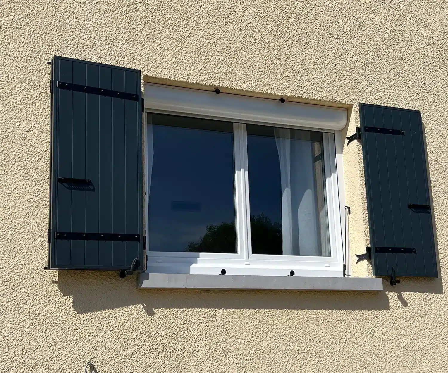 Détail de volets battants ouverts, pentures et arrêts sur une fenêtre