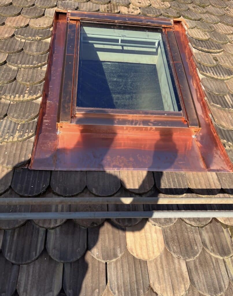 Vue de détail d’une fenêtre de toit et de ses raccords en cuivre.